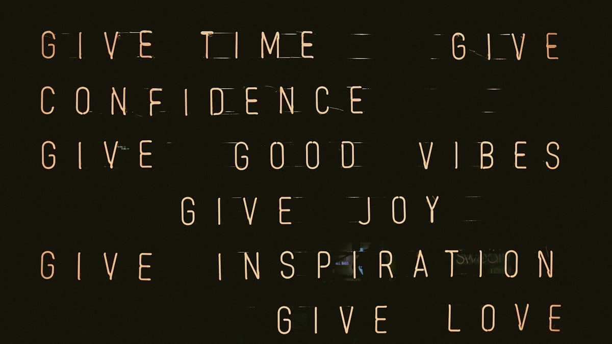 A dark wall with glowing orange text listing positive concepts like time and love